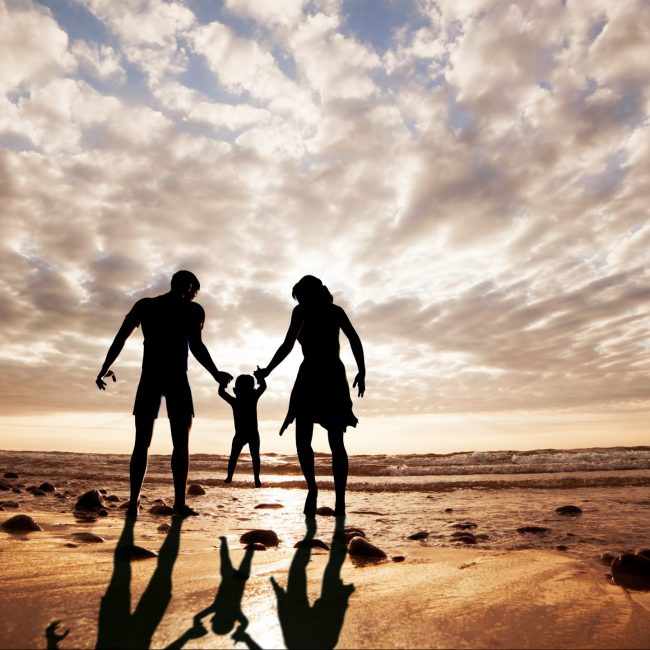 Happy family together hand in hand on the beach at sunset. Summer time, parents, child